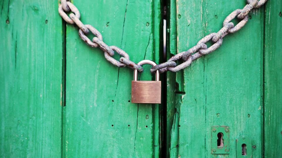 Un lucchetto con una catena su una porta di legno verde